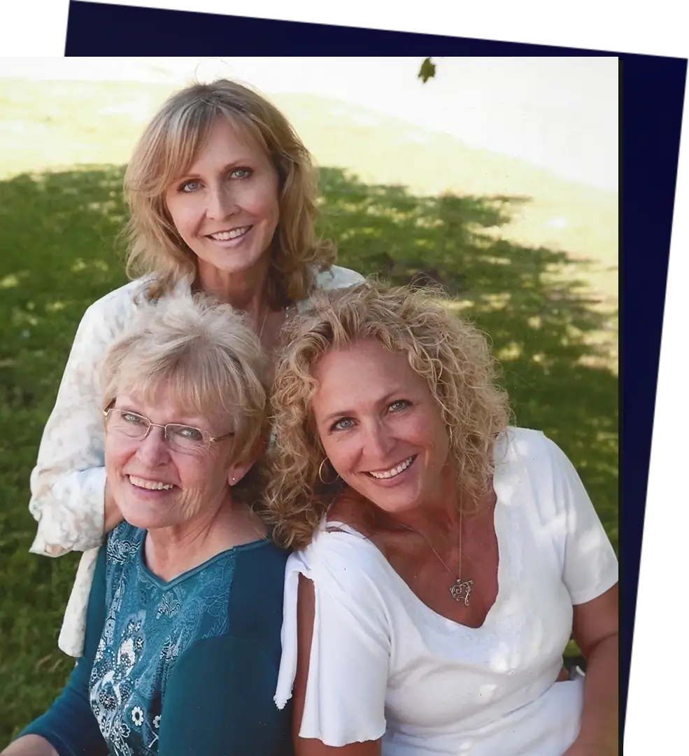 Three women pose for a picture in the grass.