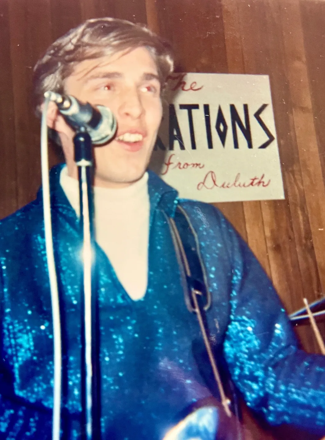 A man in blue shirt and microphone on stage.