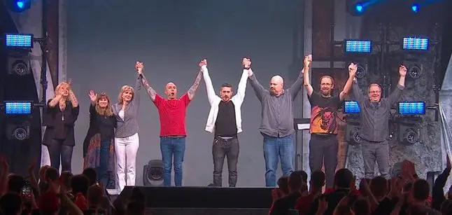 A group of people holding hands on stage.